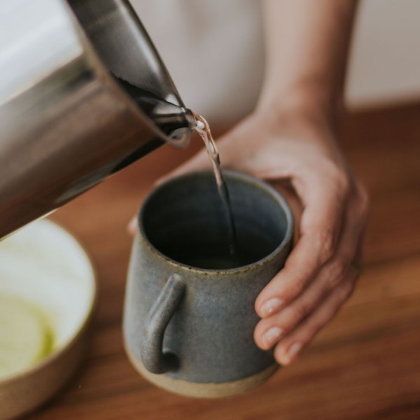 Hot water poured from a kettle into a mug