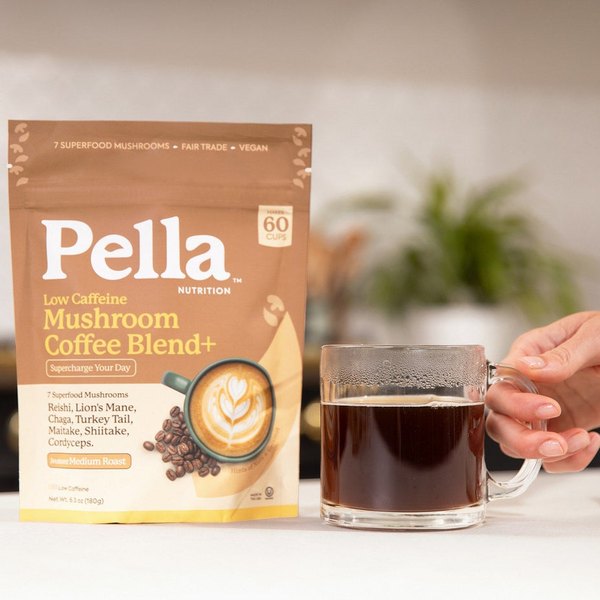 Black coffee in a glass mug next to a Pella Low Caffeine bag