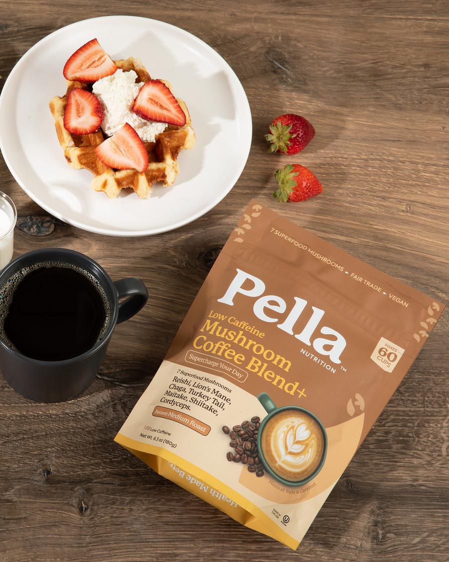 A bag of Pella Regular mushroom coffee next to a mug of coffee and breakfast