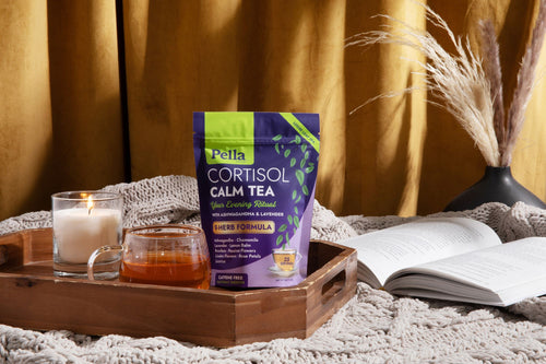 Cortisol Calm Tea pouch beside a glass of brewed tea on a knit blanket
