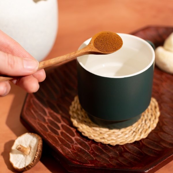 A scoop of Pella mushroom coffee going into a mug